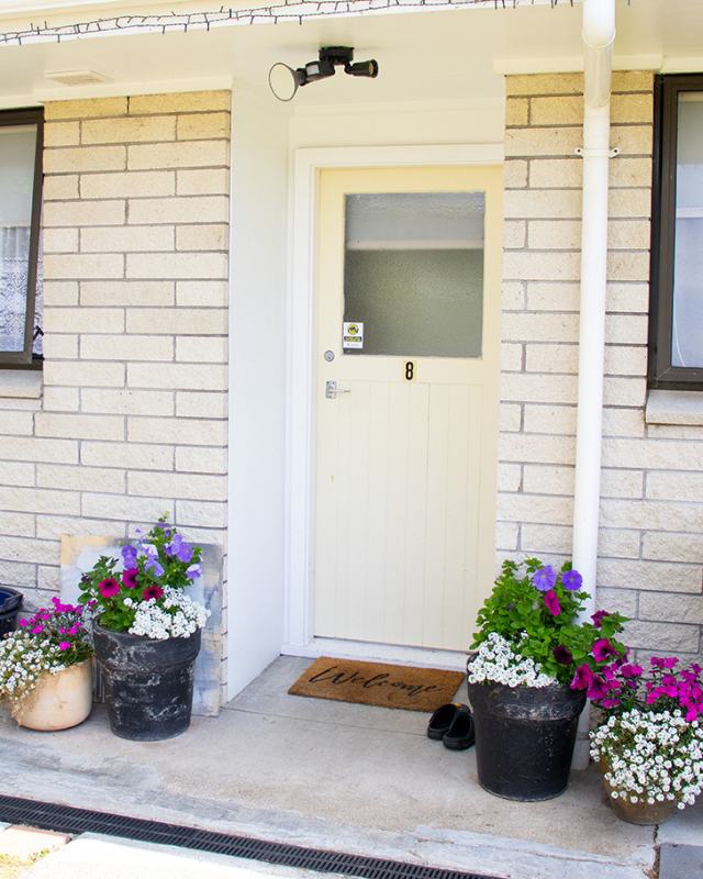 Housing exterior with welcome mat and flowers