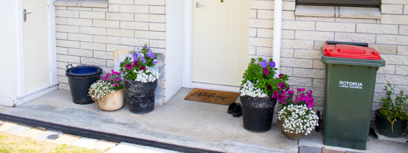 A house with flowers and bin outside